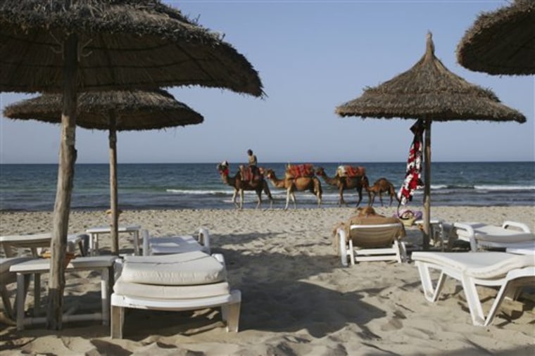 In this photo taken Sunday, July 9, 2011 a group of camels walks down a mostly empty beach on the island of Djerba, Tunisia. 
